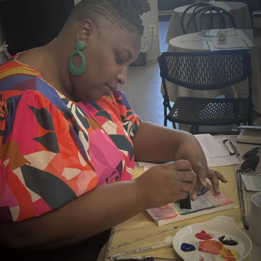 Two people painting and making cards together at a long café table